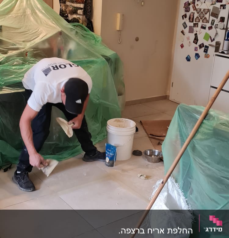 אדם משפץ רצפה עם דלי, מטאטא ושק מלט